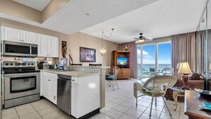 A modern kitchen with a central island, a dining area with a view, and a living room with a balcony.