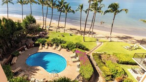 A pool area with lounge chairs, a swimming pool, and a view of the beach and ocean. - Maui Condo Ocean and Park Views Kealia Unit 205 Tranquil Beach Front Resort (Kihei)