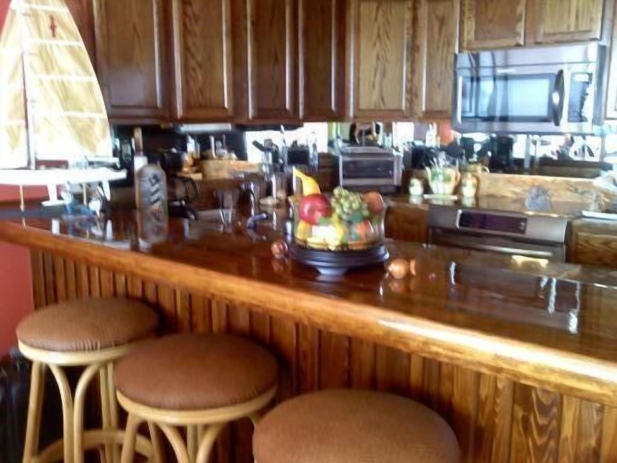 A kitchen with wooden cabinets, a stainless steel refrigerator, and a fruit bowl on the counter.