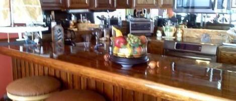 A kitchen with wooden cabinets, a stainless steel refrigerator, and a fruit bowl on the counter.