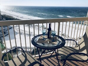 A balcony with a glass table and chairs overlooking a beach. - Beachfront-pools-hot tubs-cafe-tiki bar-onsite beach service (Destin)