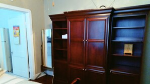 A bedroom with a bed, a wardrobe, and a small cabinet.