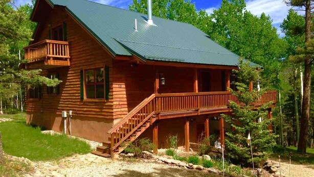 A wooden cabin with a balcony, a staircase, and a chimney. - Charming Mountain Cabin (Angel Fire)