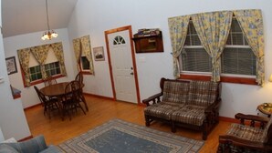 Een woonkamer met een eettafel, twee stoelen, een bank en een kamerkleed met een patroon.