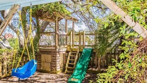 A wooden play structure with a slide and a swing.