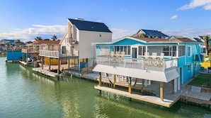 A waterfront property with multiple buildings connected by walkways over water. - Canal Front Home with Private Pool & Boat Slip (Galveston)