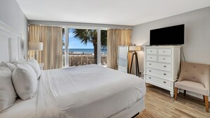 A hotel room with a large bed, a television, a dresser, and a chair.