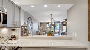 A modern kitchen with a large island, built-in appliances, and a view to the living area.