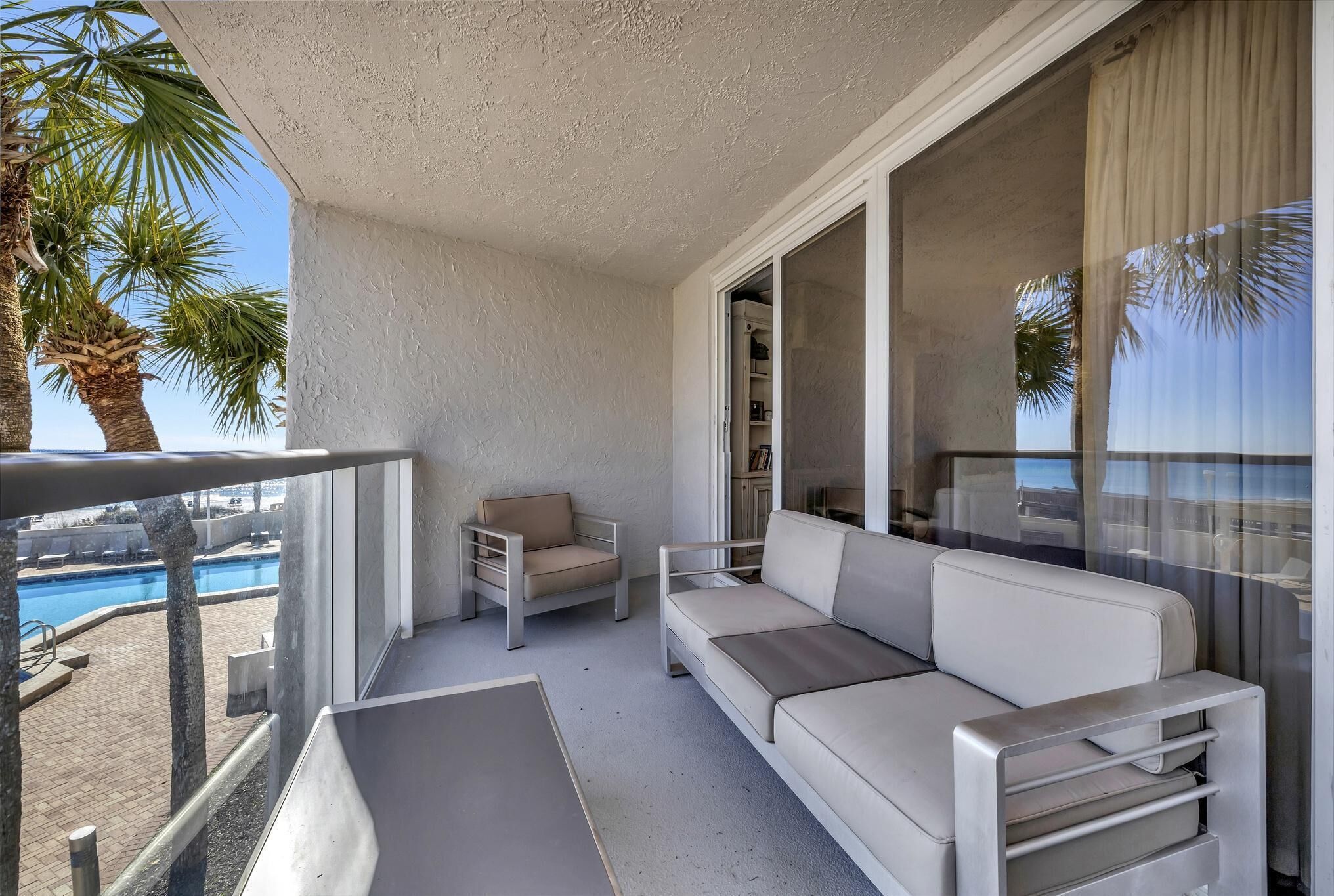Un balcon avec un canapé blanc, une chaise et une rambarde en verre.