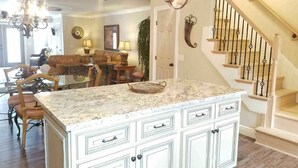 A spacious living room with a large island, a staircase, and a chandelier. - 153 Grand Island Blvd ~ Total Reno~Custom Kitchen~Granite~WiFi (Panama City Beach)