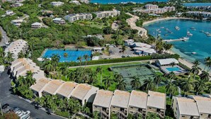 An aerial view of a resort with multiple buildings, a swimming pool, and a marina with boats.