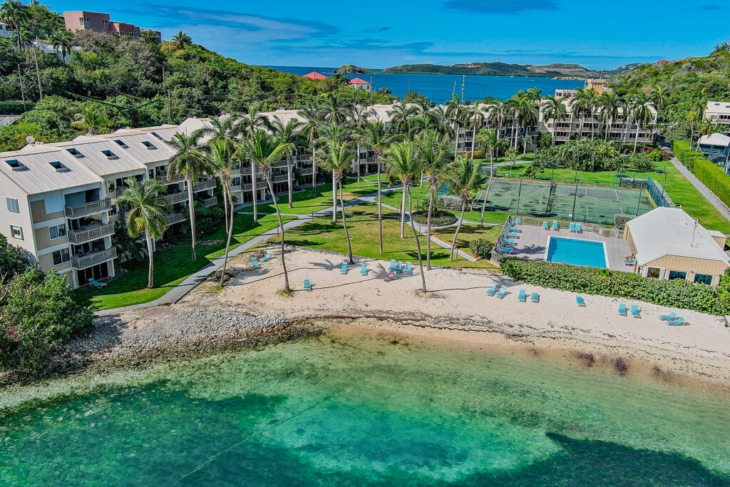 Ein Resort mit mehreren Gebäuden, einem Strand und einem klaren, blauen Meer.