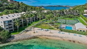 A resort with multiple buildings, a beach, and a clear blue sea.