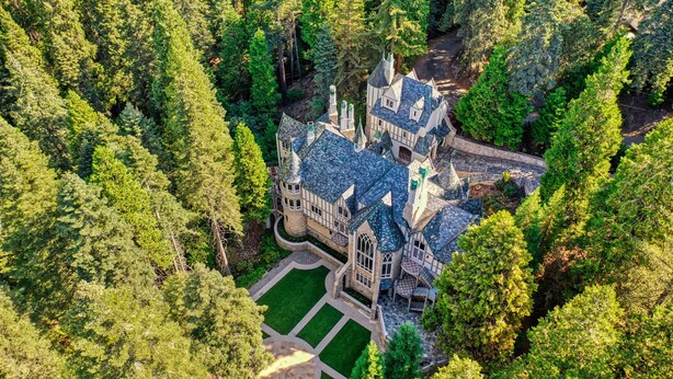 Une vue aérienne d’un grand bâtiment ressemblant à un château, entouré d’une forêt dense.