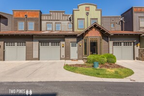 A two-story building with a garage, a small porch, and a well-maintained lawn.