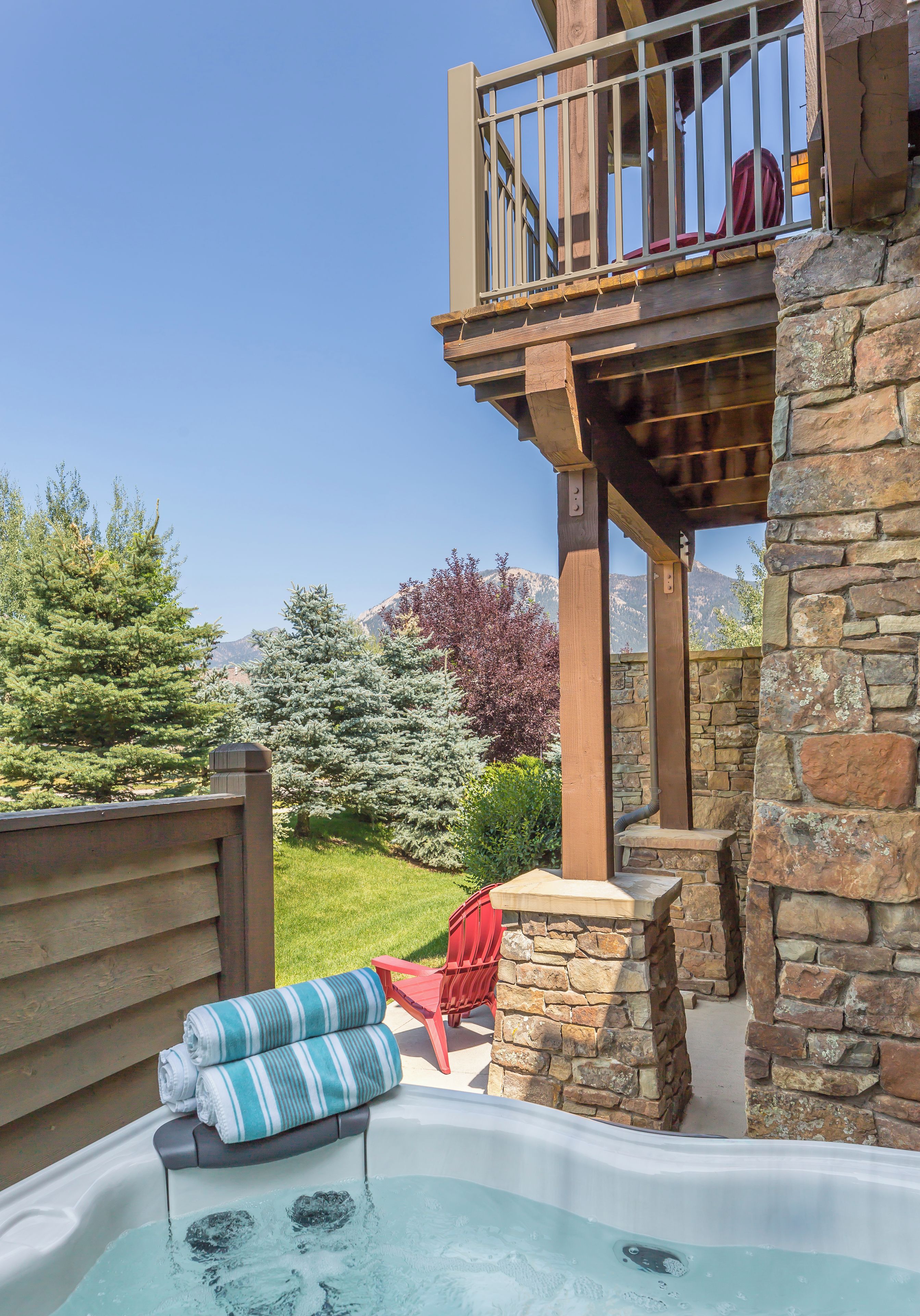 A hot tub with a stone wall and a wooden deck.