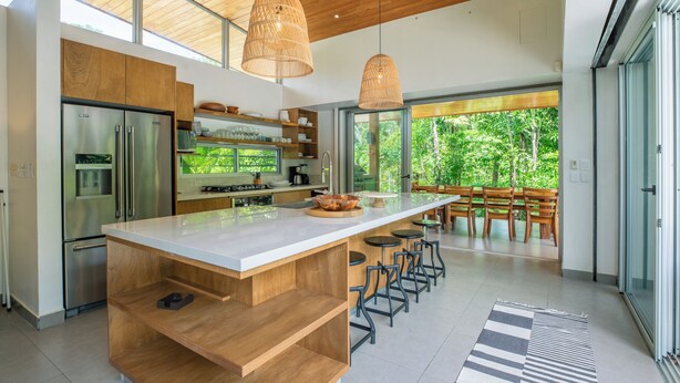 A modern kitchen with a large island, stainless steel appliances, and a view of the outdoors. - Modern Family Home w/pool, steps to beach in private community (Guanacaste Province)