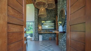 A hallway with a checkered floor, stone walls, wooden doors, and a hanging light fixture. - Modern Family Home w/pool, steps to beach in private community (Guanacaste Province)