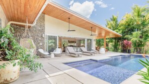 A modern house with a swimming pool, outdoor seating, and lush greenery. - Modern Family Home w/pool, steps to beach in private community (Guanacaste Province)
