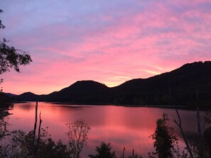 Un lac paisible au coucher du soleil, avec des montagnes en arrière-plan.