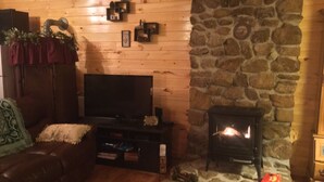 A cozy living room with a stone fireplace, a television, and a comfortable couch. - 2BR +loft  Cottage in the mountains Va Creeper Trail, HOT TUB, ATV rentals,  (Mountain City)