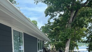 A wooden deck with a railing, a view of a body of water, and a building with large windows. - 4 Bed and 3 Bath  - Lakefront with private dock (Camdenton)