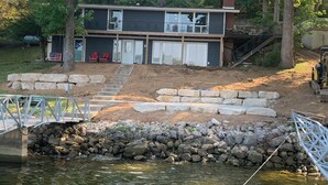 A two-story house with a dock and a stone retaining wall. - 4 Bed and 3 Bath  - Lakefront with private dock (Camdenton)