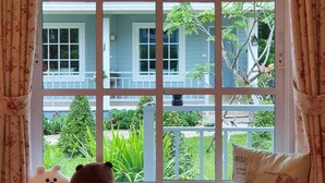 A window with a view of a house and garden. - Little Cottage (Chanthaburi)