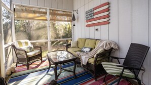 A sunroom with wicker furniture, a glass table, and a colorful striped rug. - Come to the cottage! 3BR2BA - Bethany West. Pool, pickleball, tennis, gym. Pets! (Bethany Beach)