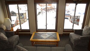 A living room with a sofa, armchairs, and a coffee table. Large windows offer a view of a snowy outdoor area. - Breckenridge Peak 8 True Ski-In Ski-Out At Over 10,000 Ft. (Breckenridge)