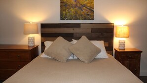A neatly made bed with a wooden headboard, two bedside tables with lamps, and a painting above the bed. - Breckenridge Peak 8 True Ski-In Ski-Out At Over 10,000 Ft. (Breckenridge)