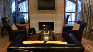 A living room with a fireplace, leather sofas, a coffee table, and a flat-screen TV mounted on the wall. - Breckenridge Peak 8 True Ski-In Ski-Out At Over 10,000 Ft. (Breckenridge)
