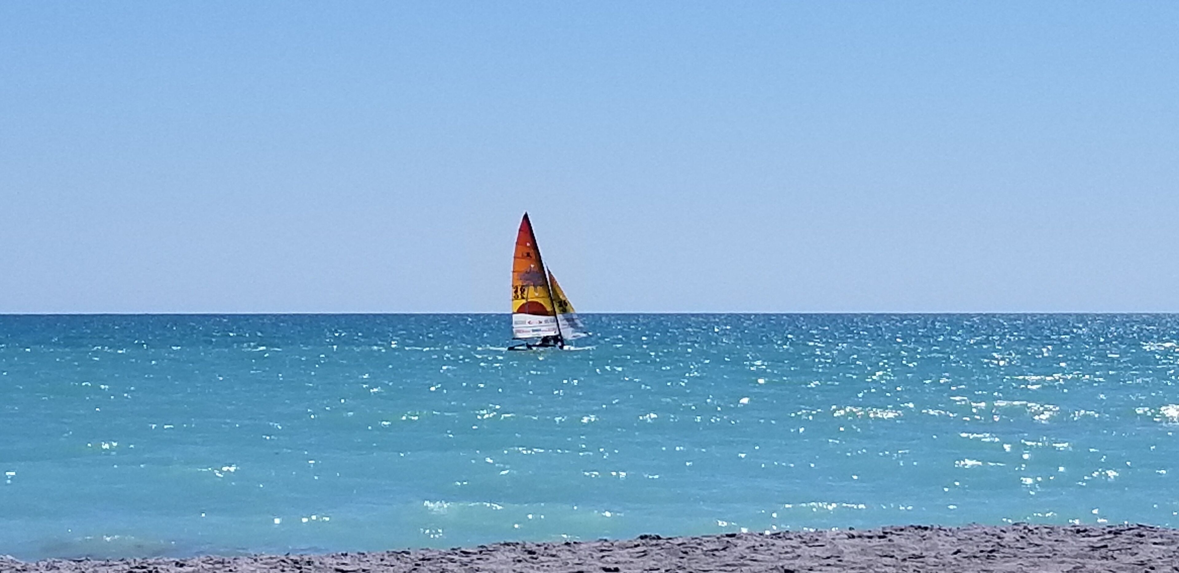 Un voilier sur une mer calme, sous un ciel dégagé.