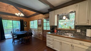 L’intérieur d’un chalet en bois comprend un coin repas, une cuisine et de grandes fenêtres.