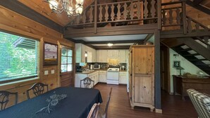 L’intérieur d’un chalet rustique comprend un coin repas, une cuisine et une chambre à coucher située en mezzanine.