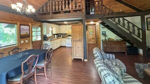 Une cabane en bois spacieuse comprenant un coin repas, une cuisine et un salon.