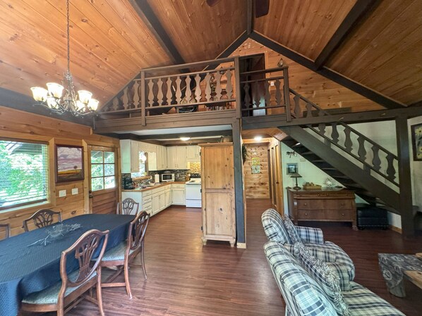 A spacious wooden cabin with a dining area, kitchen, and living room. - Hummingbird Hideaway - Lake Pets Hike Fish (Almond)
