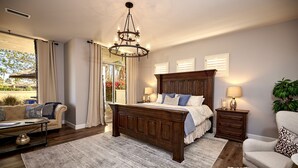 Une chambre à coucher avec un grand lit, un lustre, un canapé, un fauteuil, une table de chevet et une vue sur l’extérieur.