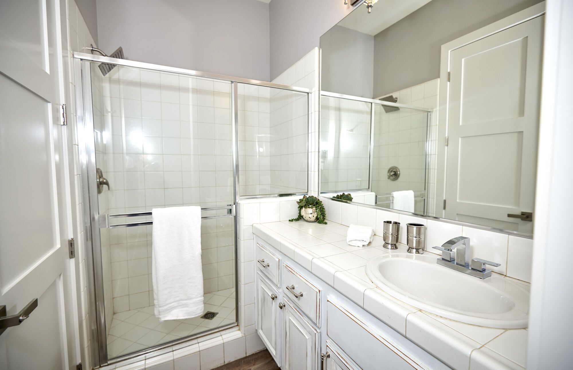 A modern bathroom with a glass shower enclosure, a white sink, and a large mirror.