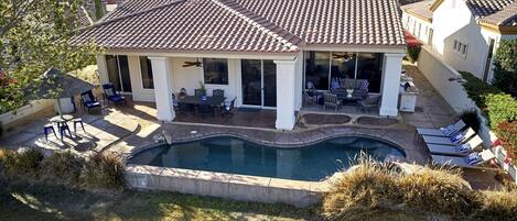 A house with a swimming pool, patio furniture, and a view of mountains.