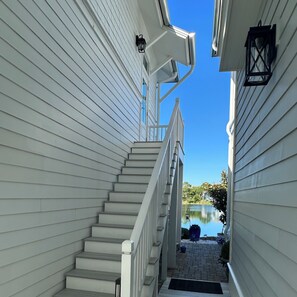 A narrow outdoor staircase leading to a deck with a view of a body of water. - Your personal complimentary beach loungers on an uncrowded beach are ready! (Panama City Beach)