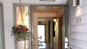 A wooden door with a 'WELCOME' mat and a hanging flower basket.