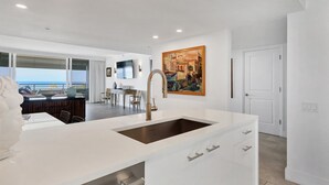 A modern kitchen with a large island, a dining area with a view, and a painting on the wall. - 2/2 Beachfront, VIEWS, Pool, Private Beach Access (Longboat Key)