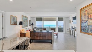 A spacious living area with a large window overlooking the sea, a dining area with a marble table, and a cozy seating area with a wooden bench. - 2/2 Beachfront, VIEWS, Pool, Private Beach Access (Longboat Key)