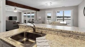 A modern kitchen with a granite countertop, stainless steel sink, and a view of the outdoor balcony.