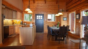 Interior de una cabaña de madera con cocina, comedor y una isla central.