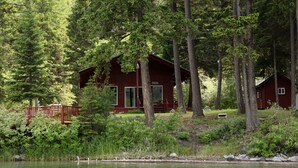 Una cabaña rodeada de un bosque denso y un lago.