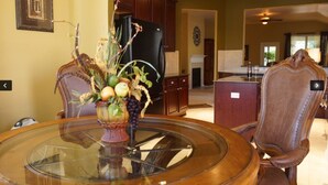 A dining area with a glass table, chairs, and a fruit centerpiece. - The Place to Relax in San Antonio, only 10 min away from Six Flags Fiesta Texas! (San Antonio)