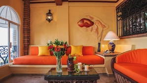 A room with orange sofas, a glass coffee table, a wall-mounted lamp, and a fish mural. - On Los Muertos beach (Puerto Vallarta)