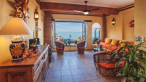 A spacious living area with a view of the ocean, a ceiling fan, and a wooden coffee table. - On Los Muertos beach (Puerto Vallarta)
